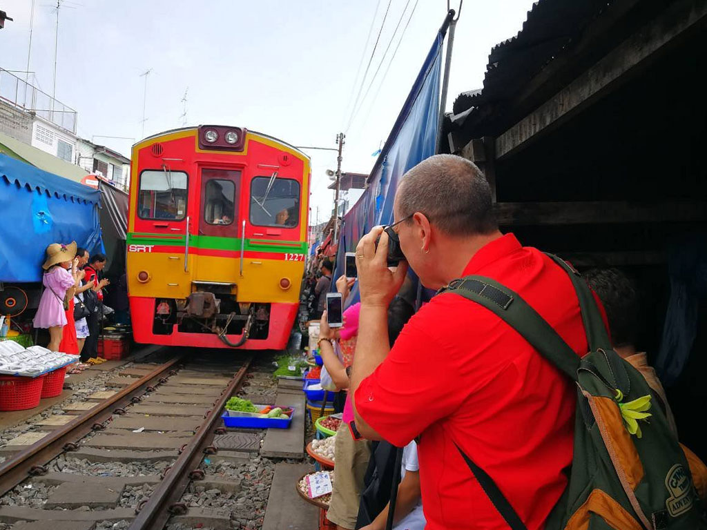 Maeklong Railway Market with vendors folding stalls as train passes through