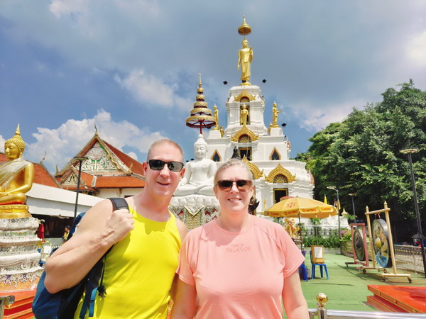Cyclists visiting a beautiful local temple with golden Buddha statues and ornate white architecture in Bang Krachao