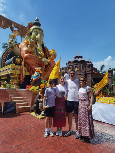 Local people praying at a shrine with ornate serpent statues and offerings at a Bangkachao temple