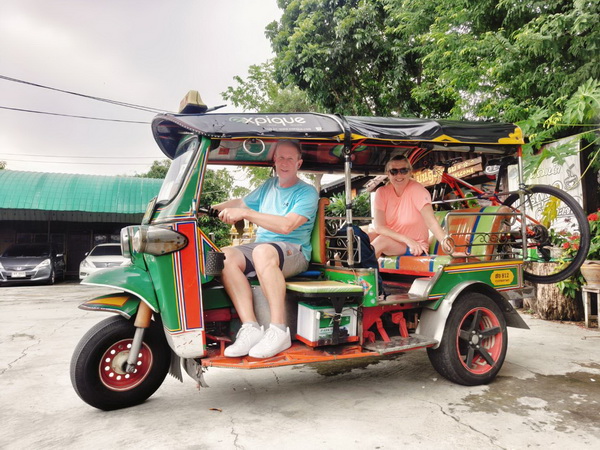 Cyclists enjoying a ride in a colourful Tuk Tuk through Bangkok streets on the way to Bangkachao island