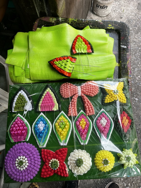 Colorful handmade Thai crafts including leaf-shaped ornaments and flower decorations displayed on banana leaves