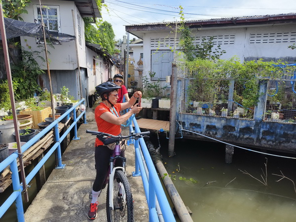Cyclist taking photos of the canals and waterways in traditional Bangkok riverside communities