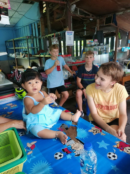 Young visitors interacting with a local Thai family in their riverside home