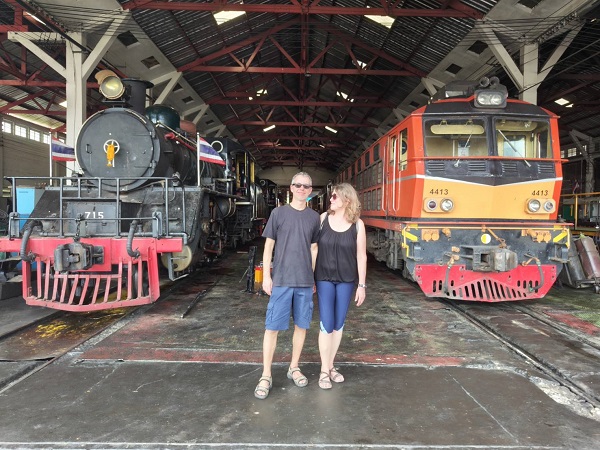 Guests posing between vintage steam locomotive and diesel train at an old railway station
