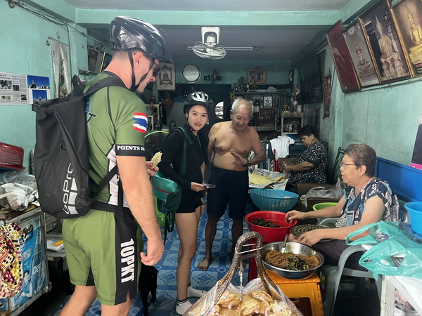 Cyclists welcomed into a local family's home to see traditional food being prepared