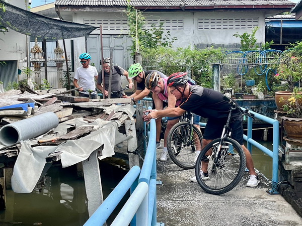 Cyclists observing traditional life along the canals in old Bangkok communities