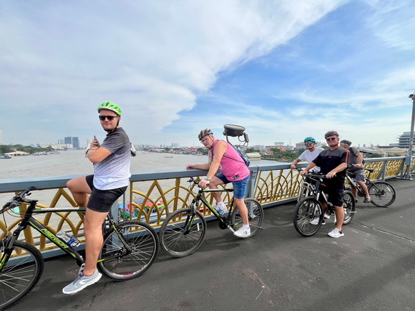 Cycling group enjoying panoramic views of the Chao Phraya river from the magnificent Rama 8 bridge