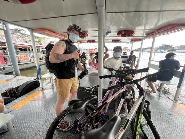 Cyclists with their bikes crossing the Chao Phraya river on a local ferry boat