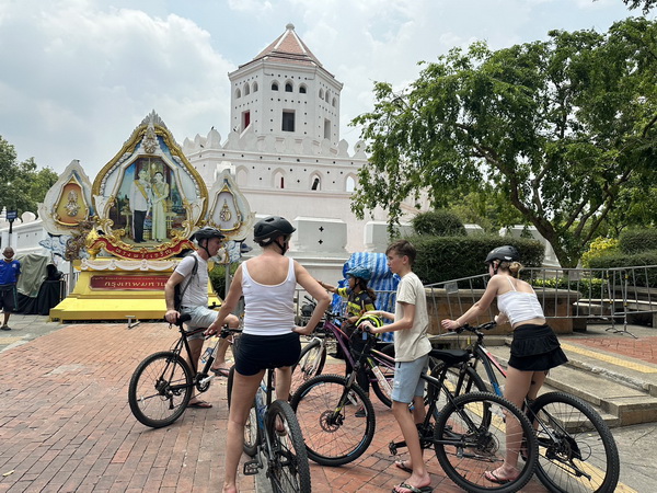 Cycling group at a historic park with white tower and ornate shrine near Khao San Road area