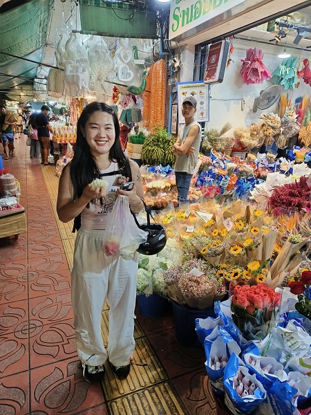 Happy guest surrounded by vibrant flower stalls at Pak Khlong Talat night market