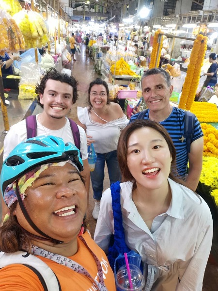 Tour guide and guests taking a selfie among the yellow marigold garlands at the flower market