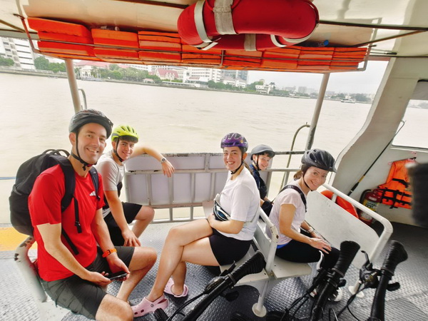 Tour group on a ferry crossing with bikes during the Bangkok Floating Markets tour