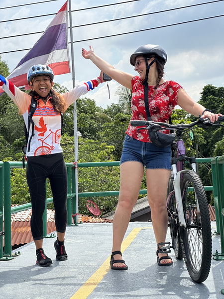 Happy cyclists celebrating on a bridge during the Bangkok Floating Markets bike tour