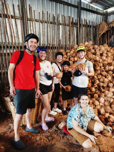 Tour group visiting a traditional coconut processing workshop during the bike tour