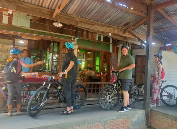 Cyclists stopping at a local vendor shop along the Bangkok canal route