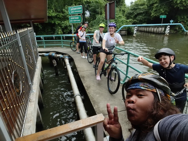 Group of cyclists posing on a canal bridge during the Bangkok Floating Markets tour