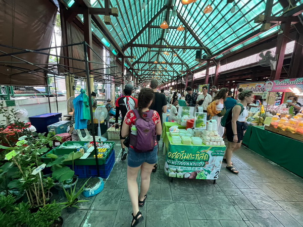 Walking through the bustling Taling Chan floating market with fresh produce and local goods