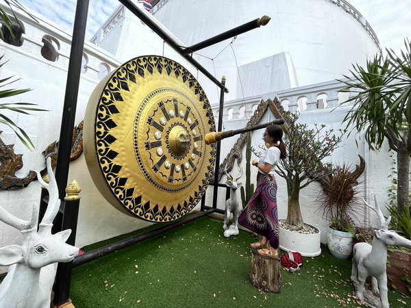 Tourist striking the giant ceremonial gong at the Golden Mountain temple grounds