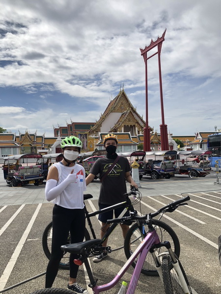 Cyclists posing with their bikes in front of the iconic Giant Swing and Suthat Temple in Bangkok