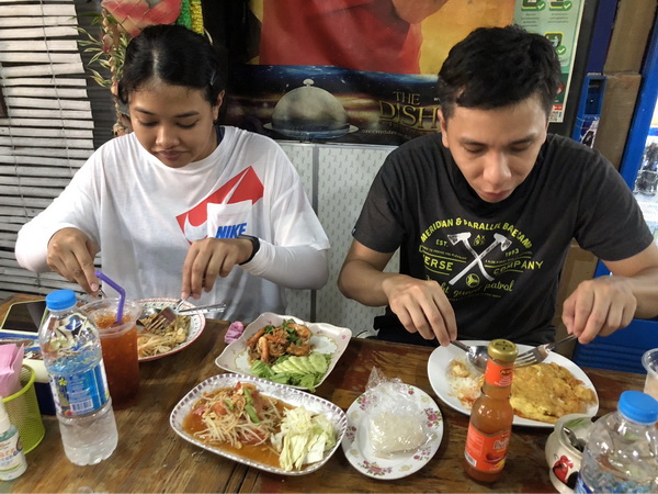 Tourists enjoying a delicious Thai lunch with papaya salad, pad thai, and fried dishes at a local restaurant