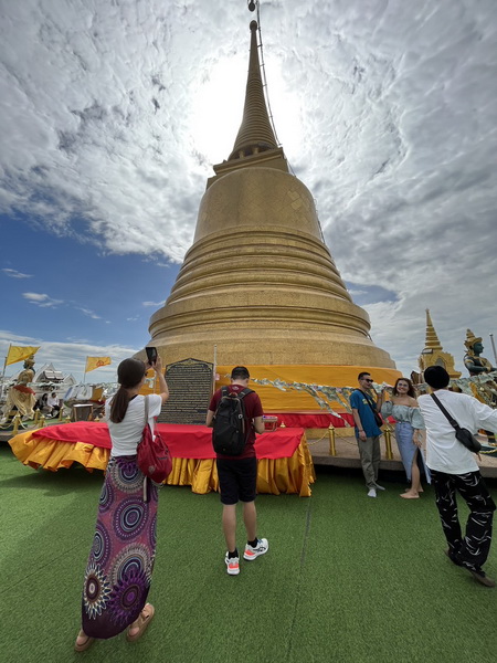 Tourists taking photos at the golden chedi stupa on top of the Golden Mountain temple