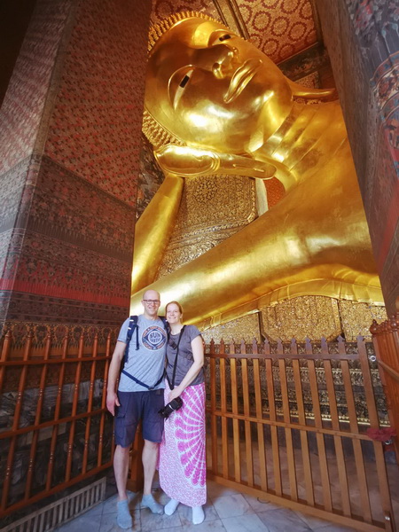 Couple posing in front of the massive golden reclining Buddha statue at Wat Pho temple