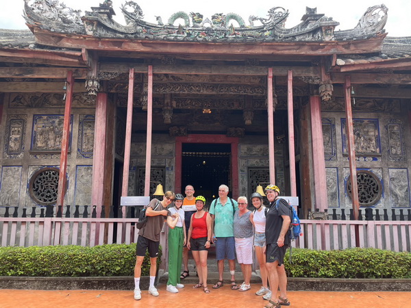 Group of cyclists posing in front of Bangkok's oldest Chinese shrine with ornate traditional architecture