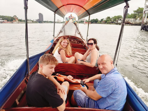 Family relaxing on a colorful long tail boat on the Chao Phraya river