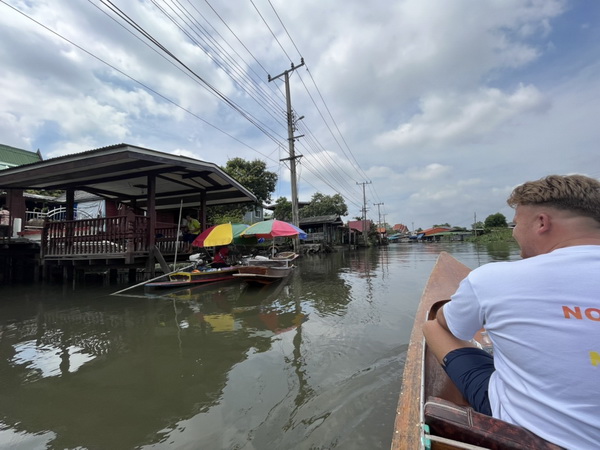View from a boat of floating vendors with colorful umbrellas along the canal