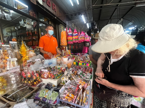 Woman browsing colorful traditional Thai goods at a local market stall