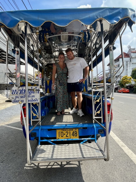 Happy couple posing in the back of a classic blue Bangkok Tuk Tuk