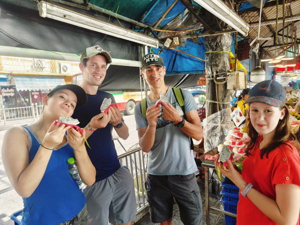 Group enjoying fresh dragon fruit at a bustling local market