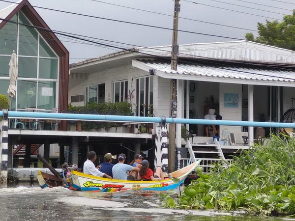 Rocket boat with passengers riding past modern canal houses