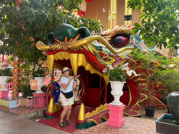 Woman posing at the entrance of a giant dragon statue at a temple