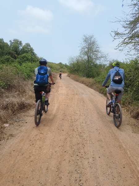 Cyclists riding on a dirt off-road trail through the Thai countryside