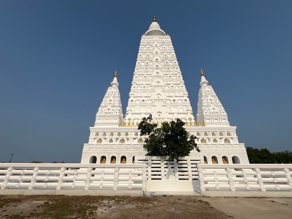 Stunning white stupa temple with intricate tiered spires against a clear blue sky