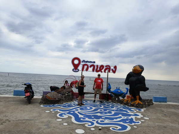 Tour group at the Mahachai waterfront with colorful statues and ocean views