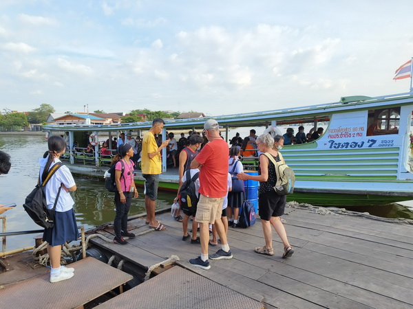 Tour group boarding a local ferry to cross the river in Mahachai