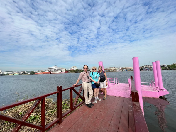 Guests waiting on a colorful pier for the ferry to cross the Ta Chin River