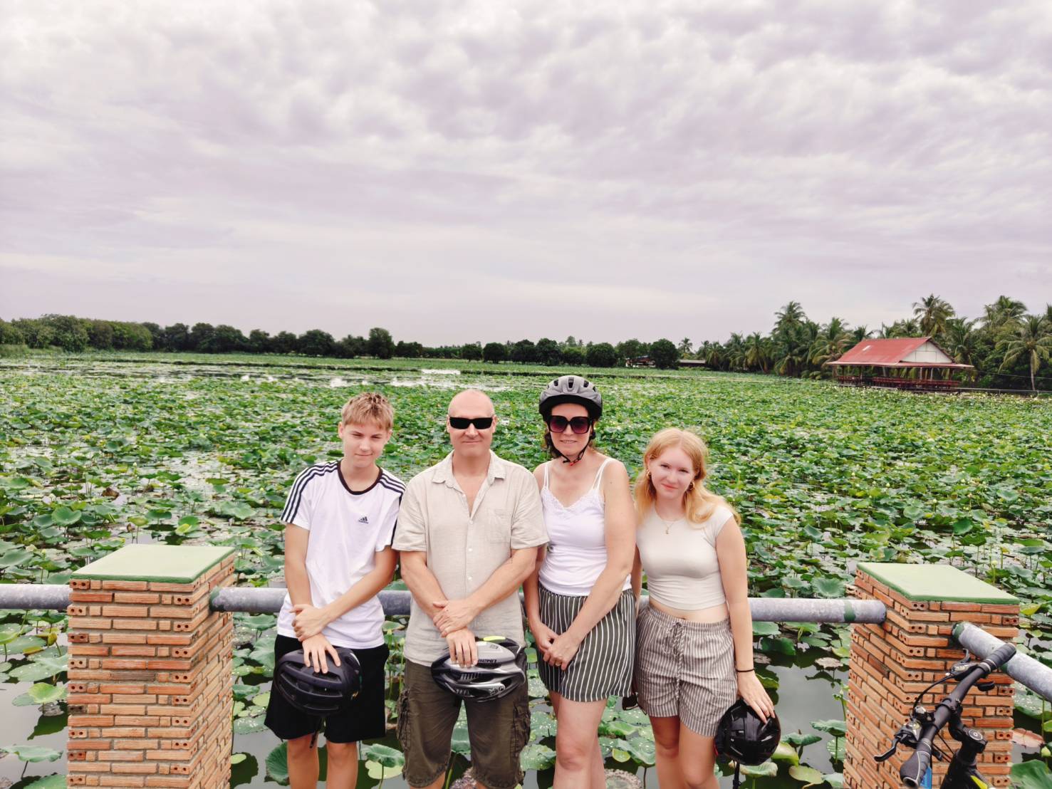 Family posing for a photo with vast lotus fields in the background in Nakhon Pathom