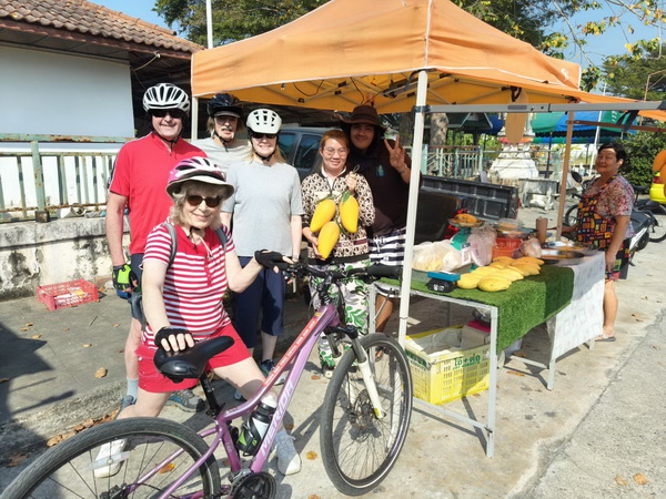 Tour group supporting local vendors and buying fresh produce at a roadside stall in Nakhon Pathom