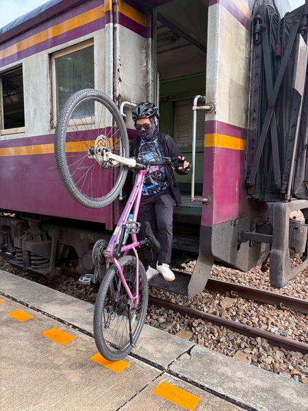 Guide carrying a bicycle off the local train at Nakhon Pathom station