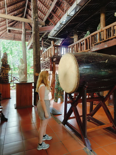 Young visitor striking the giant ceremonial drum at the Woodlands museum in Nakhon Pathom