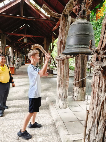Young boy striking a large traditional bell for good luck at the Woodlands museum