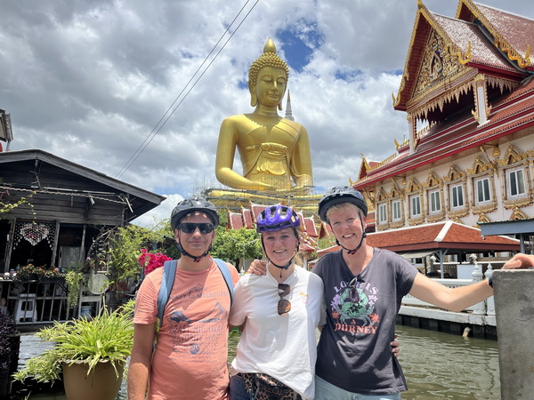 Cyclists posing with the giant golden Buddha at Wat Paknam Phasi Charoen