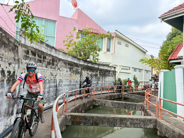 Cyclists navigating narrow paths next to canals in the Paknam neighbourhood