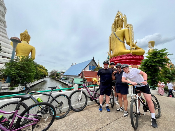 Tour group with bikes crossing the bridge of the main canal near Wat Paknam