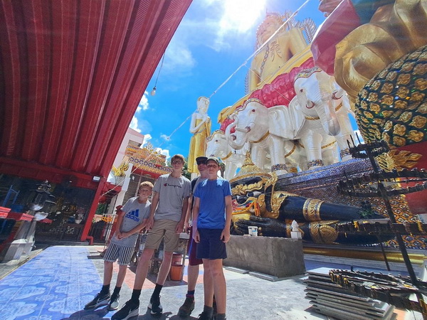 Family posing with the three white elephants and guardian statue at Wat Paknam