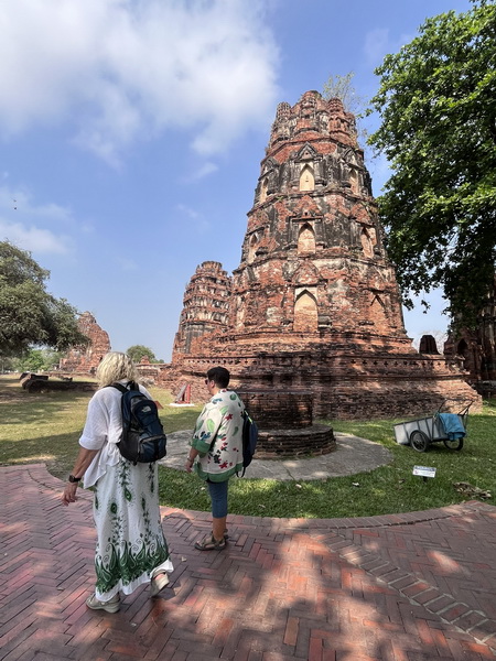 Guests admiring the ancient red-brick chedi towers of Wat Chaiwatthanaram temple