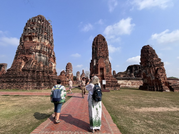 Guests walking toward the magnificent ancient prang towers of Wat Chaiwatthanaram in Ayutthaya